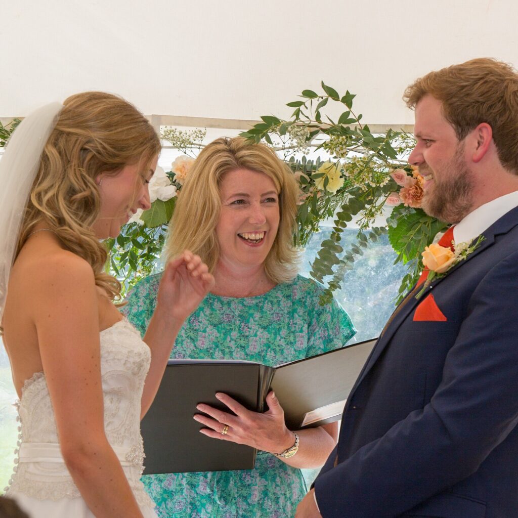 A wedding couple laughing and smiling, with their humanist celebrant (Jane Blackman)