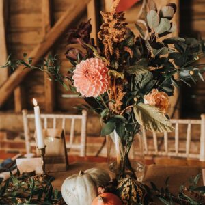 Beautiful autumnal wedding decor with table flowers, candles and squashes 