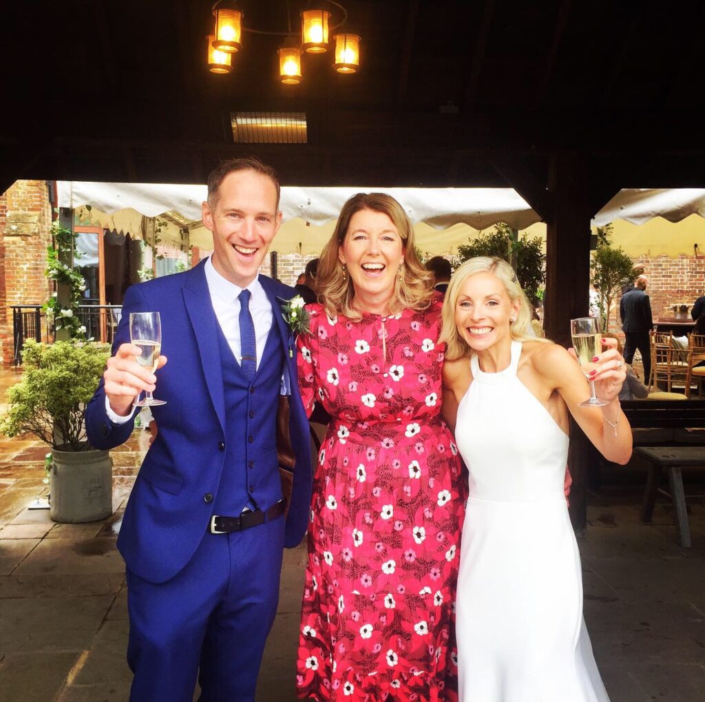 A happy couple celebrating after their ceremony, with champagne in hand, with their humanist wedding celebrant (Jane Blackman)